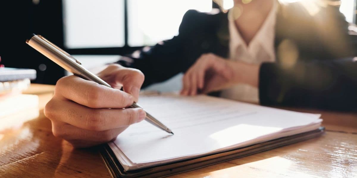 Close-up of a person signing documents, representing preparation for the Bildungsgutschein application.