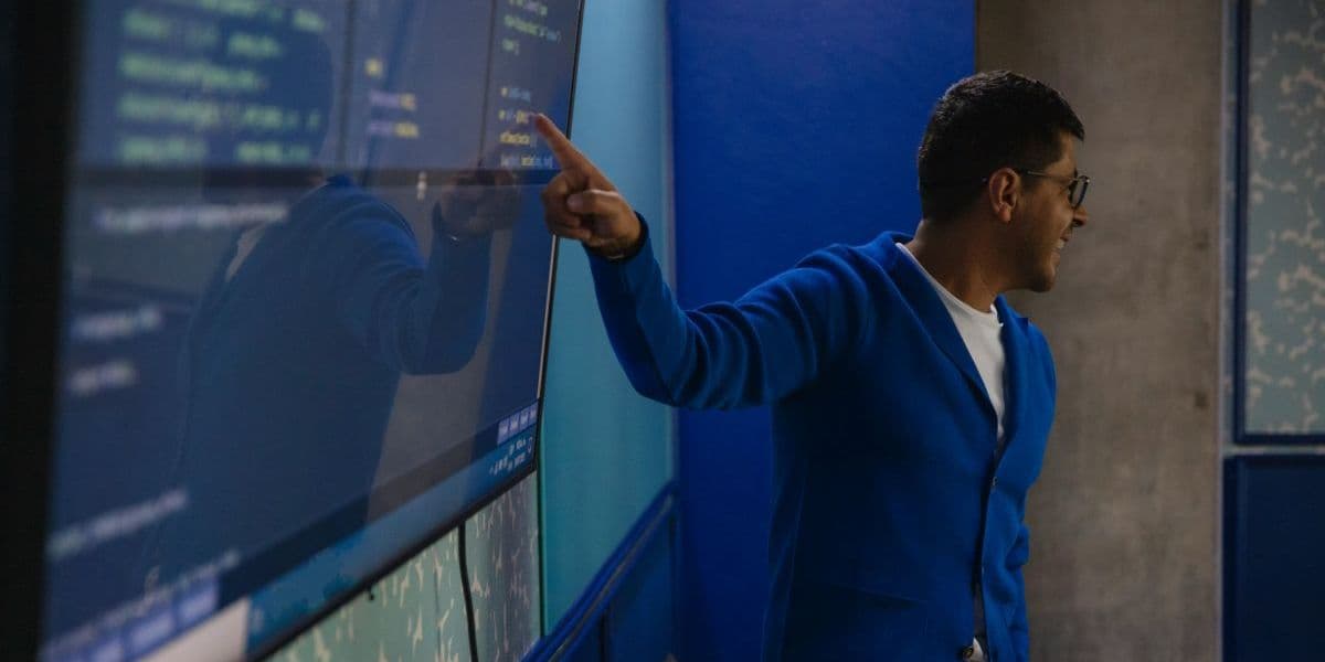 Man in a blue jacket pointing at a computer screen during a training.
